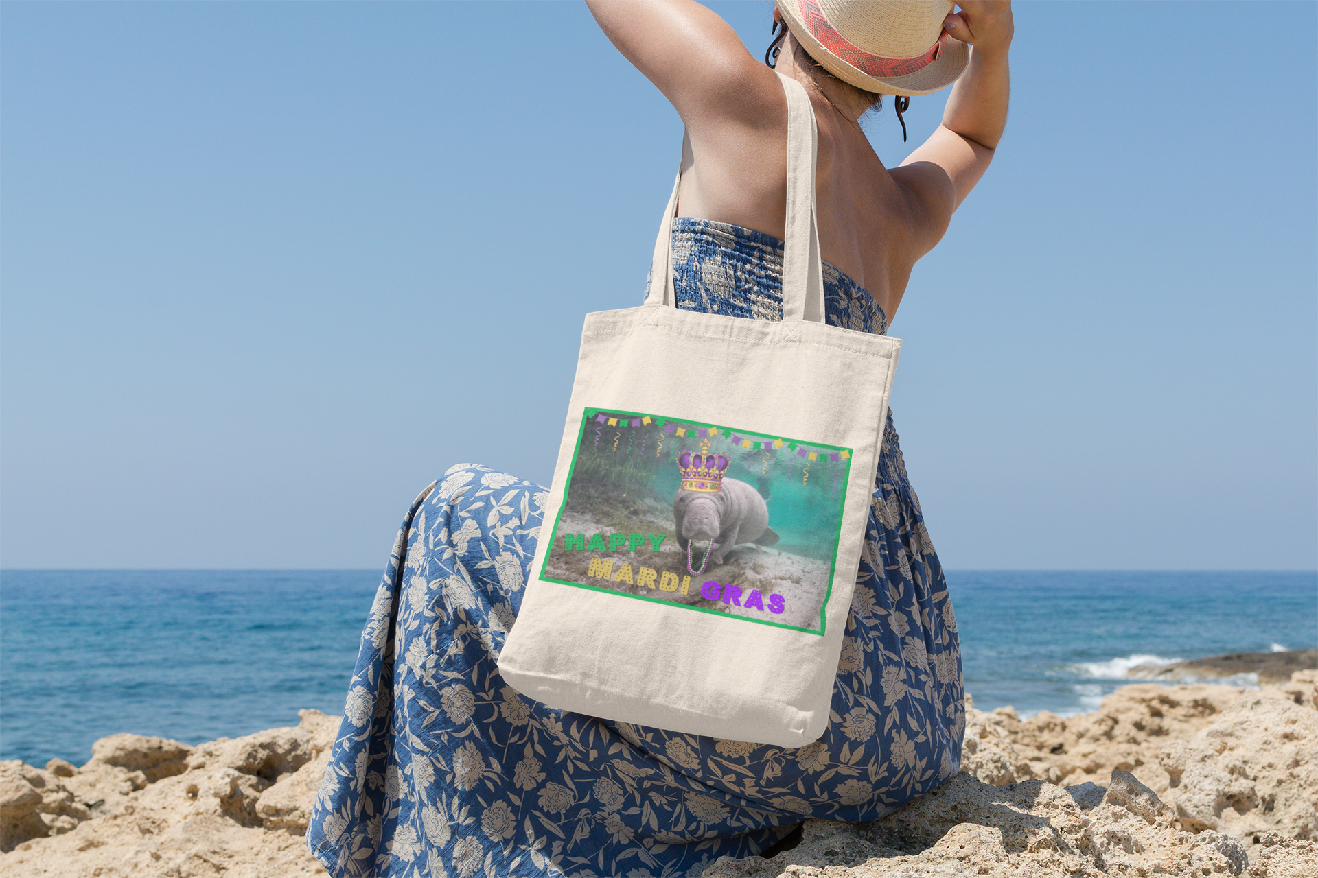Happy Mardi Gras Manatee Tote Bag, model sitting on beach overlooking ocean