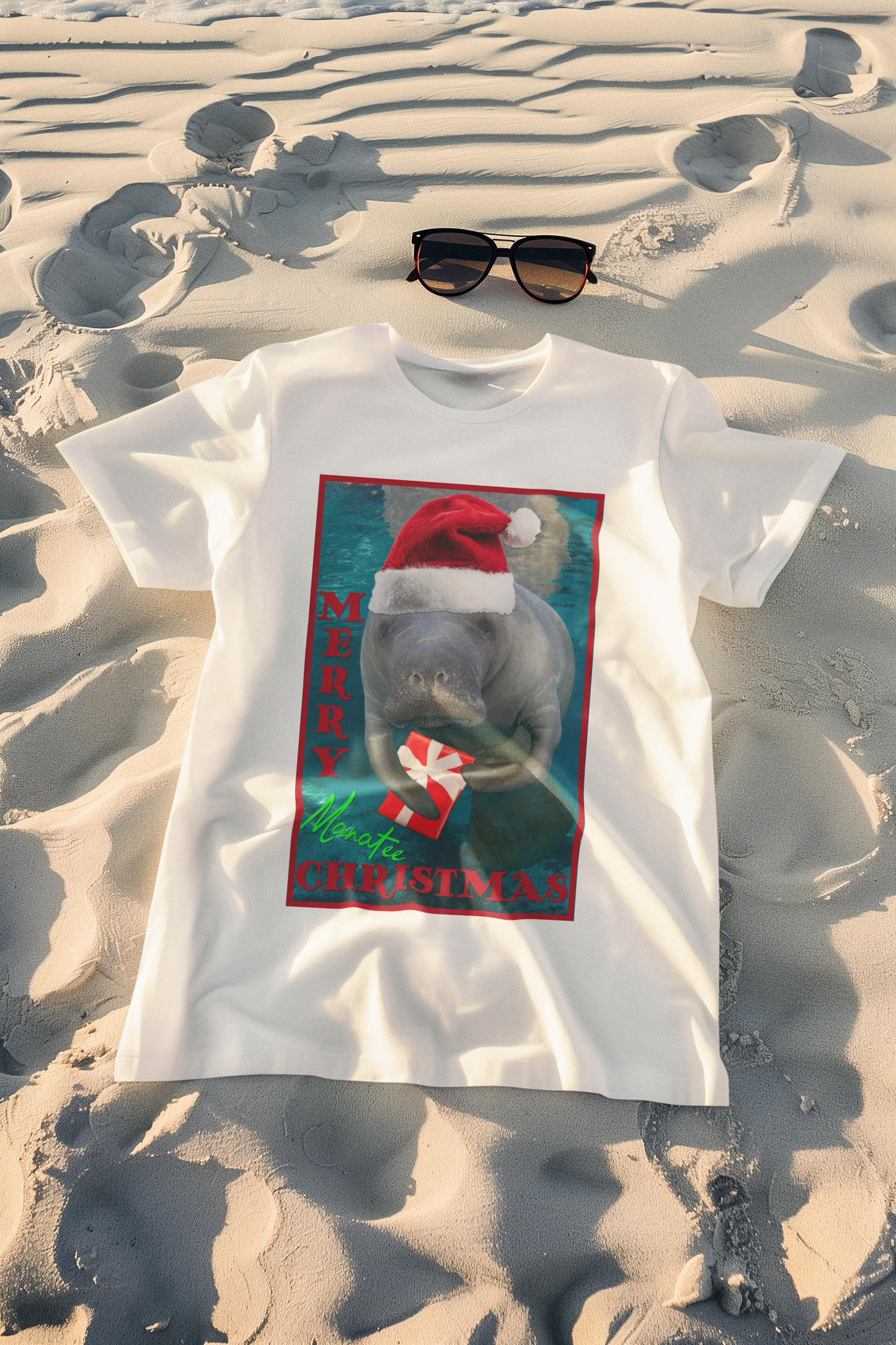 Merry Christmas Manatee Tee, white t-shirt on beach with sunglasses